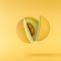 Fresh ripe Galia Melon falling in the air isolated on yellow background