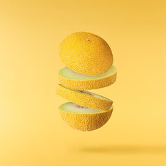 Fresh ripe Galia Melon falling in the air isolated on yellow background