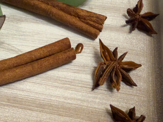Close-up of cinnamon sticks and star anise placed on a light wooden surface.