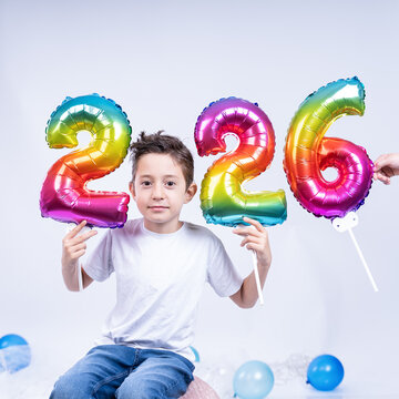 A little boy holds colorful balloons showing the coming new year 2026