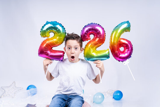 A little boy holds colorful balloons showing the coming new year 2026