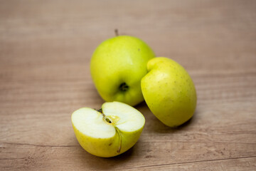 Whole and sliced green apples on a wooden table, showing fresh texture and juicy interior. Suitable for themes like healthy food, fruits, breakfast, snacks, and natural ingredients.