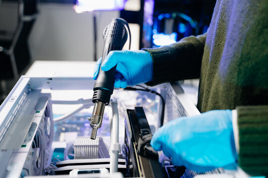 Closeup of technician testing computer motherboard with multimeter in modern lab, representing precision, innovation, and professional electronic repair service.