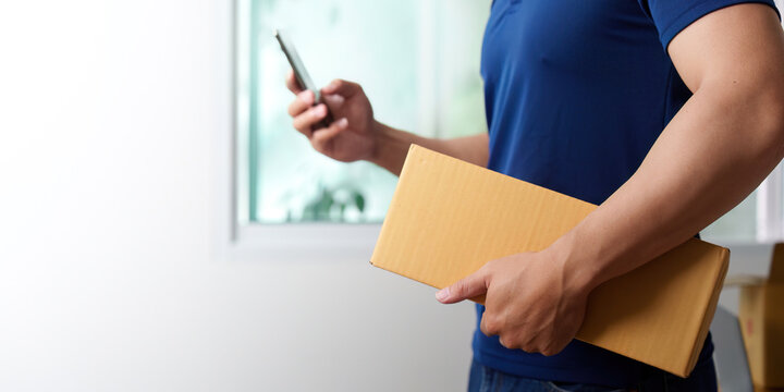 Delivery Process. Person holding a package and smartphone, coordinating logistics.