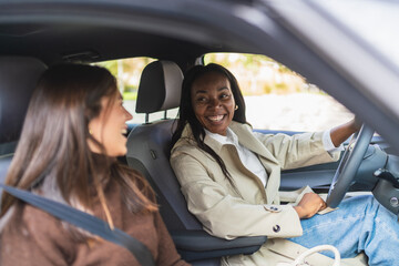 Smiling diverse women friends enjoying car ride, sharing conversation and happy moments during a journey