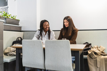 Diverse women friends sitting at a cafe table, enjoying a casual conversation and laughing together during a coffee break