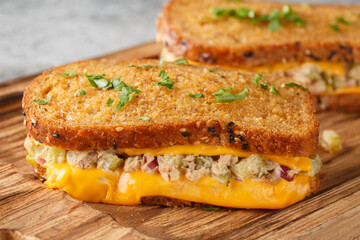 Tuna melt toast made from rye bread, canned tuna with vegetables and mayonnaise and melted cheese close-up on a wooden board on the table. Horizontal