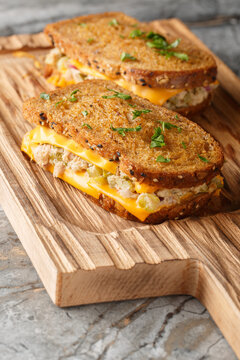 classic tuna melt sandwich with cheese on buttery rye bread closeup on wooden board on the table. Vertical