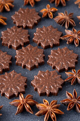 Christmas sweet food background. Anise stars and chocolate candies top view. Brown color