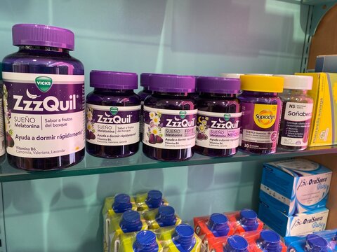 Palma, Spain - November 25, 2025: vicks zzzquil sueno melatonin sleep aids and other supplement bottles lined on a pharmacy glass shelf, retail sleep support display