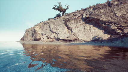 Serene rocky coast meets tranquil water, creating stunning reflections under a bright sky. The peaceful scene captures natures beauty and invites relaxation at the shore.