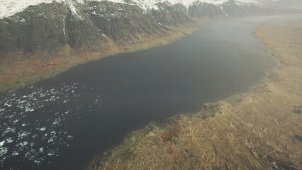 Mountainous landscapes cradle a serene lake, reflecting the sky. Snow capped peaks rise majestically around the water, creating a stunning natural panorama in this remote location.