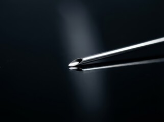 Close up of a sharp metal medical needle on black background
