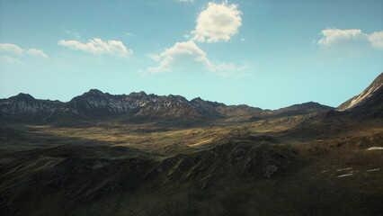 A vast and breathtaking mountain landscape stretches across the horizon. The sun casts a warm glow on the peaks and valleys, highlighting the natural beauty of the rugged terrain.