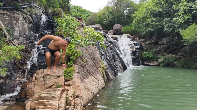 Man makes his way along rocks waterfall. Wilderness escape. Waterfall creates calming white noise. Remote natural setting promises deep relaxation. Ultimate tranquil getaway. Concept deep relacation