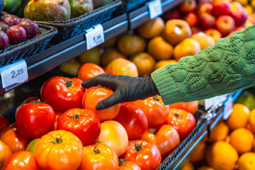 Person wearing disposable glove choosing fresh tomatoes in store