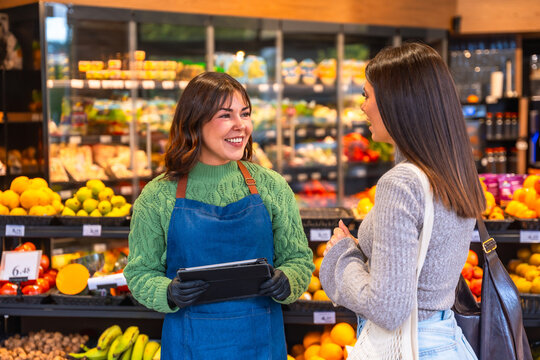 Supermarket employee helping customer at fresh produce section