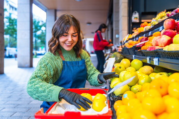 Smiling woman worker arranging fresh apples in grocery store