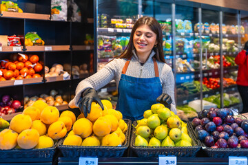 Woman sorting fresh fruits in supermarket produce section