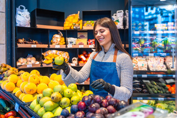 Happy worker arranging fresh produce in grocery store
