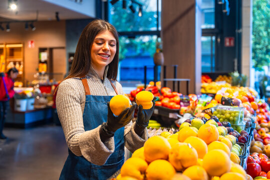 Grocery store employee arranging fresh produce in a supermarket