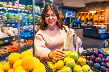 Woman shopping for fresh pears using reusable net bag