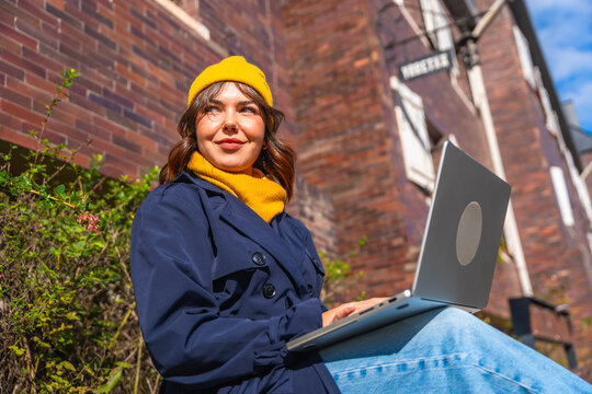 Woman working remotely with laptop outdoors in city