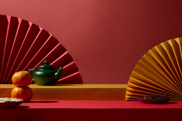 Decorative fans with fruits and festive props arranged neatly on a red surface. Perfect for designers wanting a ready-to-use Lunar Festival visual asset. Blank space for display product