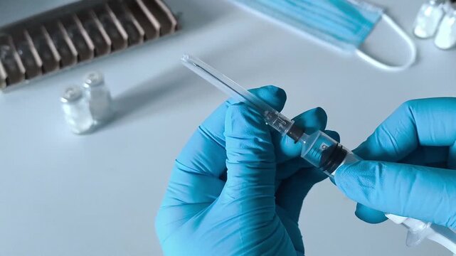 Hands in blue medical gloves open the syringe cap. Concept of treatment, vaccination, immunization of the population