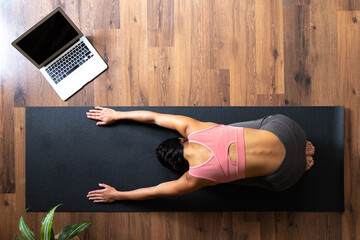 Woman doing yoga online class on mat at home
