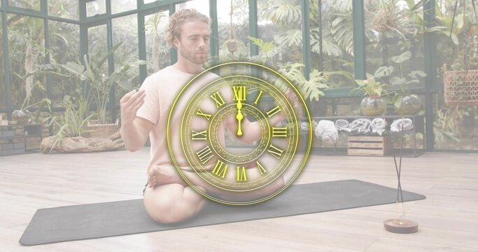 Sitting light-tee man meditating on black mat in conservatory, with clock overlay and incense smoke