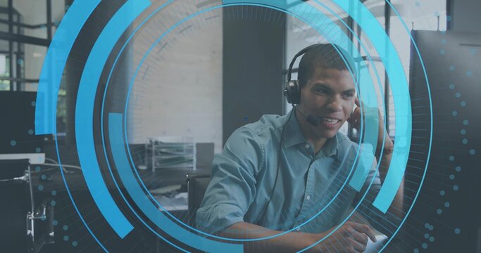 Speaking support agent wearing blue shirt typing on keys at office desk with headset, monitors, HUD - Powered by Adobe