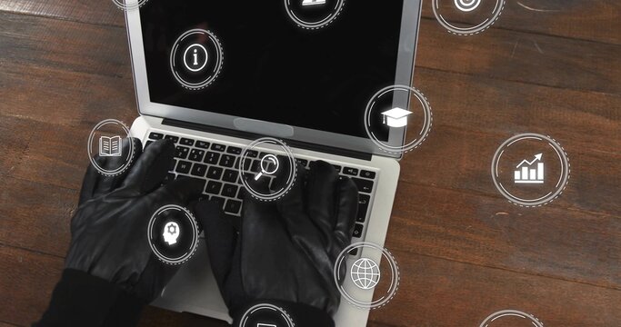 Typing black-gloved hands in dark sleeves, operating silver laptop on dark table with HUD icons