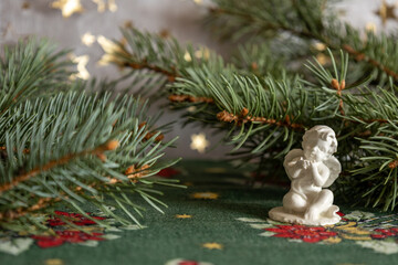 A delicate white ceramic angel figurine sits on a festive green tablecloth 