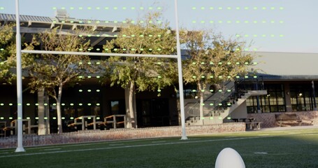 Framing white football on tee on turf at field, white metal goalpost, green markers, copy space