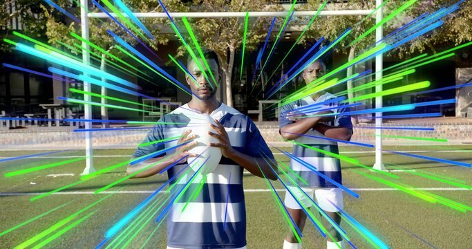 Holding ball, center player wearing navy striped jersey on grass pitch with goalposts, neon streaks