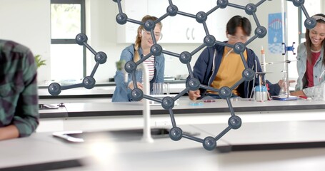 Working students in lab wearing navy and denim jackets handling glassware, with molecular model