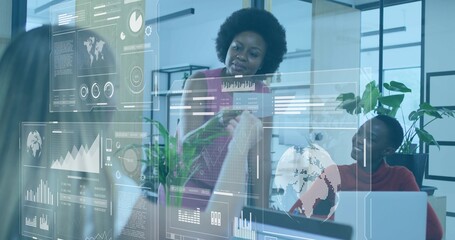 Pointing three women wearing business attire analyzing data charts and 3D globe in open-plan office