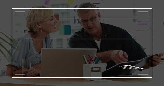 Leaning senior couple checking laptop, black folder at bright office, in light blouse, dark shirt
