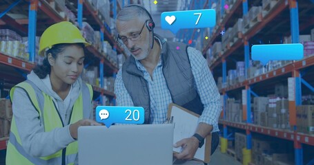 Pointing hardhat hi-vis staff viewing laptop, lead reading clip mic in warehouse with blue alerts