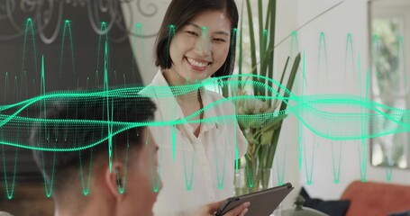 Smiling Asian woman in white blouse holding tablet, presenting in office with green wave overlay