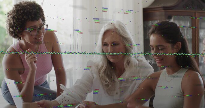 Reviewing senior woman in white blouse leaning over papers at home dining table, with laptop