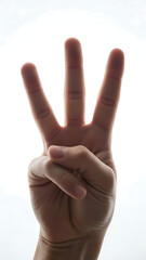 Hand gesture showing three fingers against a bright white background.