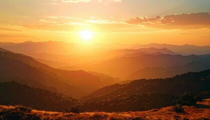 A scenic landscape featuring mountain ranges silhouetted against a vibrant sunset sky. The sun casts a warm golden glow, creating a dramatic and peaceful atmosp