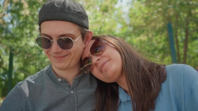 couple enjoying nature, smiling pair in park sunshine, youthful duo sharing tender moments outdoors, playful youthful couple engaging in affectionate interaction amidst sundappled park setting