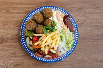 Falafel plate with hummus, fries, grilled vegetables, and salad