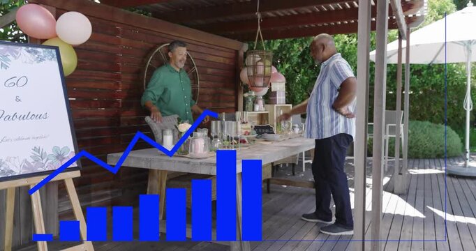 Two men arranging 60th party table on deck, striped man leaning, blue graphic growing over table