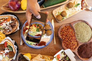 Hand taking picture of falafel plate with smartphone