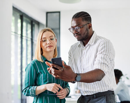 Portrait of young students or businesspeople having a meeting and using mobile phone in the office. Teamwork and success concept, portrait of a smart young businesspeople - Powered by Adobe