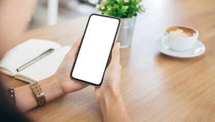Woman reading or scrolling on smartphone at a wooden table with a notebook, pen, plant, and coffee. Mockup for app or website.